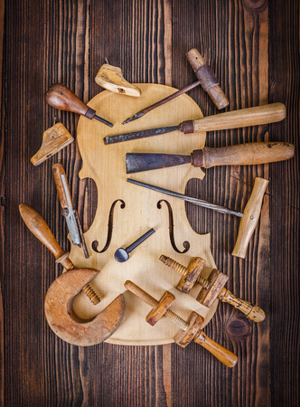 Violin belly and different work tools on wooden tableの写真素材