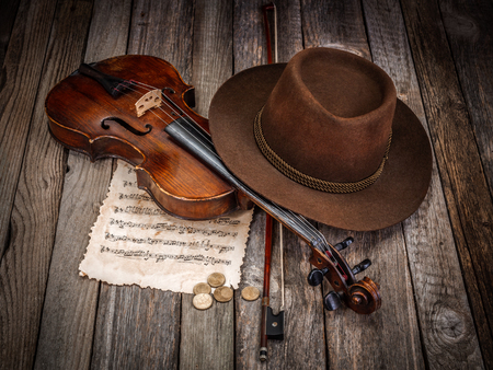 Brown musician hat, violin and coins on wooden tableの写真素材