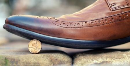 Brown leather shoe stepping on a coin standing on edge - 1 cent with the image of Lincolnの写真素材