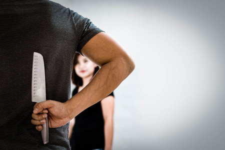 Bad Guy Hiding A Knife Behind His Back to Attack the Woman in front of Him. Selective Focus.の写真素材