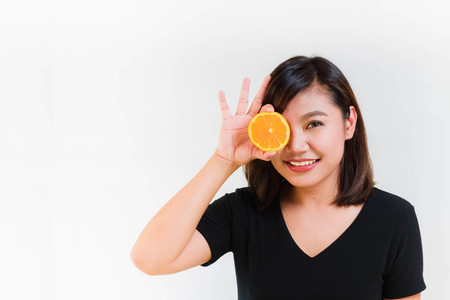 Woman Put Orange in front of Her Eye on White Backgroundの写真素材