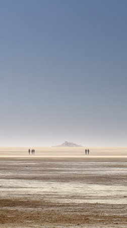 A desert mirage shimmering on horizon with people walking under clear blue sky, tranquil sceneの素材