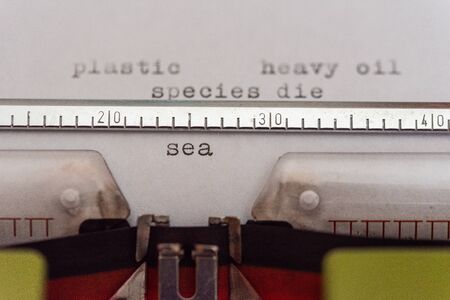 Typewriter  with a leaf and the words plastic, heavy oil, species die and sea