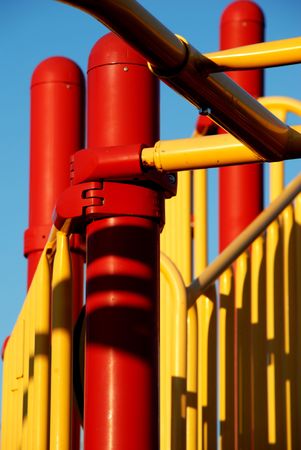Red and yellow bars at a child's playground against a blue sky.の写真素材