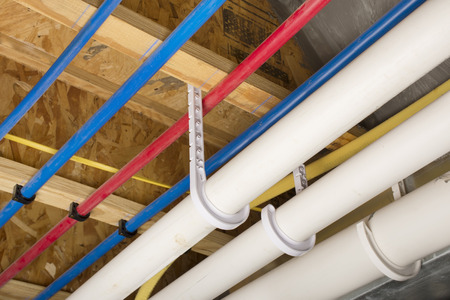 PEX and drain pipes attached to the basement ceiling of a home.