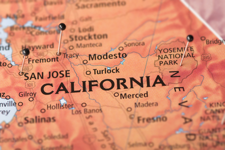 Closeup of California on a political map of the United States with pins in some cities.