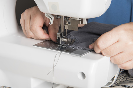 A Woman Using a modern Sewing Machine to repair clothing.の写真素材