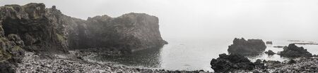 Panoramic view of Badstofa Rock Foamation and ocean on a foggy day, Iceland