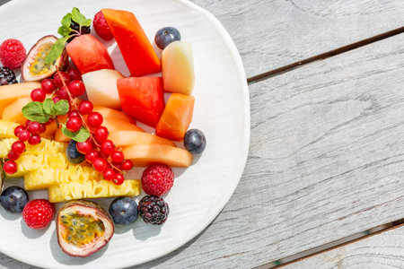 Fruit salad, simple wooden background and fresh fruits. Elegant clean fruit plate sunlight, bright grey wooden backdropの写真素材