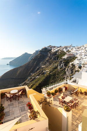 Romantic Santorini island, Greece, Europe. Amazing evening view of Fira, caldera, volcano of Santorini, Greece, soft sunlight over beautiful terrace, restaurant. Summer vacationの写真素材