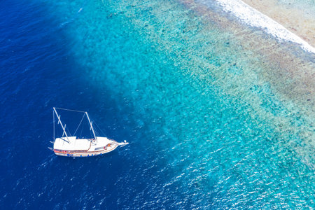 Aerial view of sailing boat anchoring on coral reef. Drone view, water sport theme. Luxury cruise and marine travel background. Beautiful nature sea ocean water. Maldives aerialの写真素材