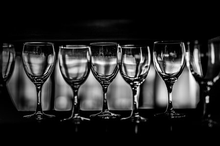 Rows of empty wine glasses on the showcase, black and white photographyの写真素材