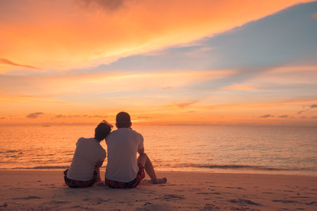 Couple in love watching sunset together on beach travel summer holidays. People silhouette, behind sitting enjoying sunset sea tropical destination vacation. Romantic couple beachの写真素材