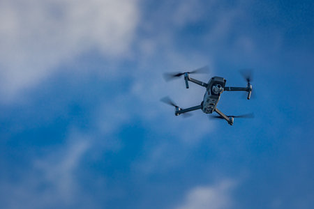 Drone flying against blue sky with copy space. Modern technology UAV with camera use for photo or...