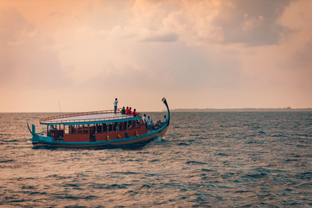 Tourist boat in sea at sunset. Wonderful Maldivian boat Dhoni on tropical blue sea, taking tourist to a sunset cruise. 08.13.21 - Faafu Atoll, Maldivesの写真素材