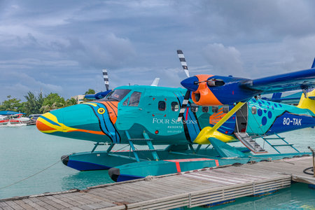 Seaplane of Trans Maldivian Airways airline is on port with overcast sky in Male. Special plane paint on seaplane, Maldives aerial transportation. Male, Maldives - 08.17.2021のeditorial素材