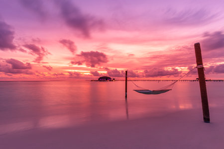 Tropical beach sunset as summer nature landscape beach swing or hammock and white sand and calm sea for beach sunrise. Romantic beach scene vacation and summer holiday concept.の写真素材