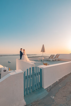 Young couple honeymoon on the most romantic island Oia Santorini, Greece. Sunset wedding landscape, beautiful wedding couple in soft colors. Love, honeymoon background. 10.05.21のeditorial素材