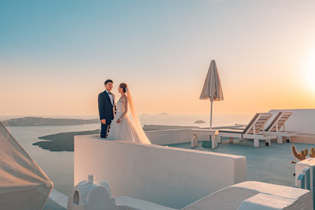 Young couple honeymoon on the most romantic island Santorini, Greece. Sunset wedding landscape, beautiful wedding couple in soft colors. Love, honeymoon background. 10.05.21のeditorial素材