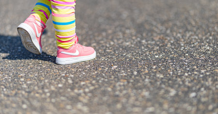 Cute little girl legs with Nike pink sport shoes and rainbow pants. Cute outdoor photo of girl playing. 04.12.21 - Provence, Franceのeditorial素材