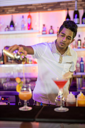 Expert barman is making cocktail at night club. Vintage portrait of bartender creating cocktails at bar. Close up of alcoholic beverage preparation. 08.17.21 - Noonu atoll Maldivesのeditorial素材