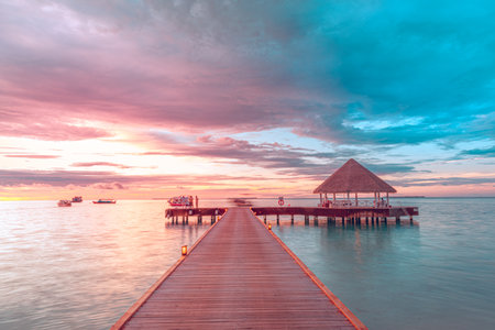 Amazing sunset sky and reflection on calm sea, Maldives beach landscape of luxury over water bungalows. Exotic seaside of summer vacation and holiday backgroundの写真素材
