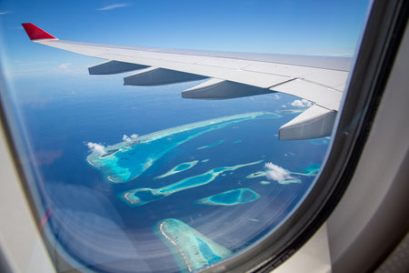 Maldives islands top view from flight airplane window. Luxury vacation destination as through window of an aircraft. Amazing Maldives island landscape and seascape. Exotic travelの写真素材
