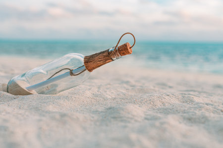 Message in the bottle washed ashore against the sun setting down. Tropical beach sea shore castaway design background. Travel conceptの写真素材