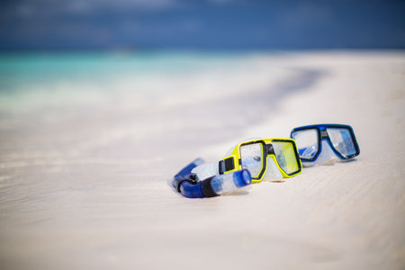 Diving goggles and snorkel gear on sandy beach. Scuba diving snorkeling. Two snorkel on white sand. Tropical nature landscape blurred sea view. Summer couple recreational activityの写真素材
