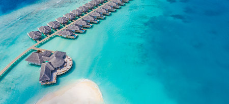 Aerial view Maldives island, luxury water villas resort wooden pier. Amazing sky ocean lagoon beach panorama. Summer vacation island travel. Paradise aerial landscape panoramicの写真素材