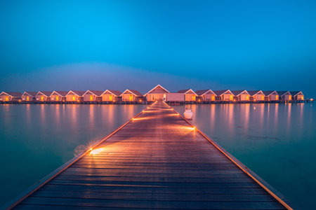 Amazing sunset panorama at Maldives. Luxury resort hotel villas pier seascape soft led lights colorful sky. Ocean lagoon, stunning romantic seascape. Relax inspire vacation beachの写真素材