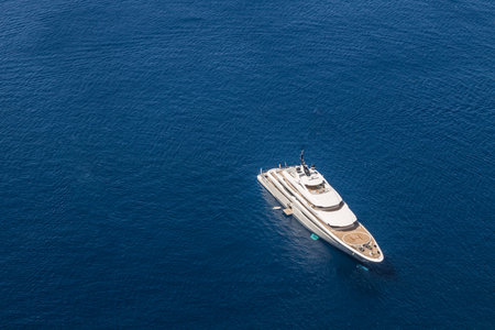 Aerial drone top down photo of luxury exotic yacht with wooden deck anchored in Aegean island with deep blue Mediterranean sea, Greece.の写真素材