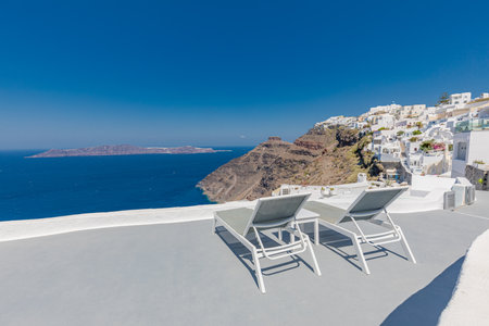 Santorini island, Oia caldera, two sun beds loungers amazing sunny Mediterranean sea view horizon recreational calm relax. Inspire beach resort hotel. Luxury Greece travel 24.07.21のeditorial素材
