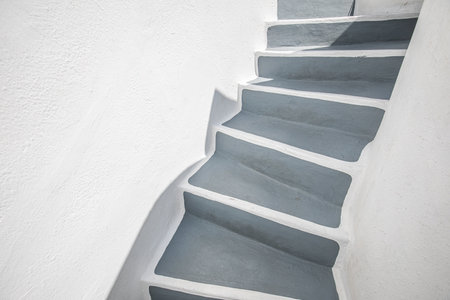 Empty stone stairway near white wall, abstract closeup in Santorini island, Greece. White architecture with gray steps. Minimal building detail. Artistic grey stairsの写真素材