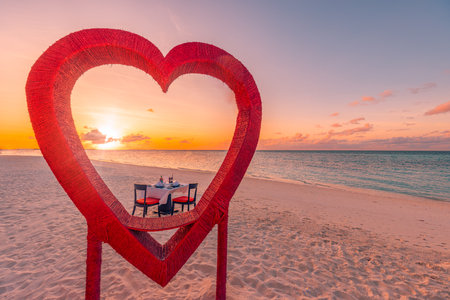 Honeymoon couples dinner private luxury romantic dinner on tropical beach Maldives. Seaside sea amazing island shore red heart shape table chairs. Romantic love destination diningの写真素材