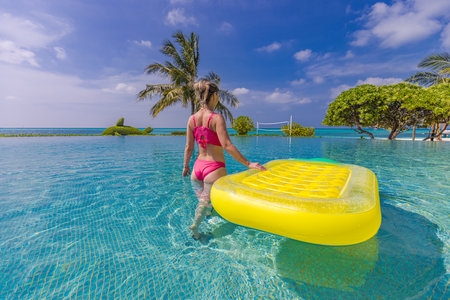 Beautiful sexy woman relaxing on rubber inflatable in pool in tropical resort. Attractive carefree...