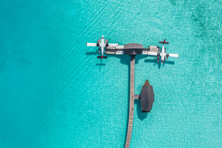 Hydroplane in crystal clear turquoise water Indian Ocean tropical islands. Top aerial view Maldives island, water villa long pier seaplanes in amazing sea lagoon. Fantastic travelの写真素材