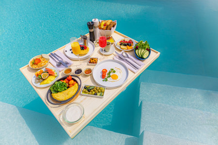 Breakfast in swimming pool, floating breakfast in luxury resort. Table relaxing calm pool water, healthy wellbeing fruit plate resort pool. Tropical couple beach leisure lifestyleの写真素材