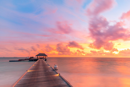 Maldives island sunset panorama. Water bungalows resort beach. Indian Ocean, Maldives. Beautiful landscape, luxury resort villas colorful sky. Summer vacation holiday travelの写真素材