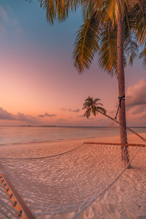 Sunset hammock hanging between palm trees tropical beach peaceful serene landscape warm golden sky perfect summer vacation escape relax carefree travel tourism tranquil retreatの写真素材