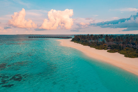 Sunset aerial tropical beach Maldives water villas island landscape sunshine palm trees sand blue sea exotic paradise luxury vacation travel relaxation serene coastlineの写真素材
