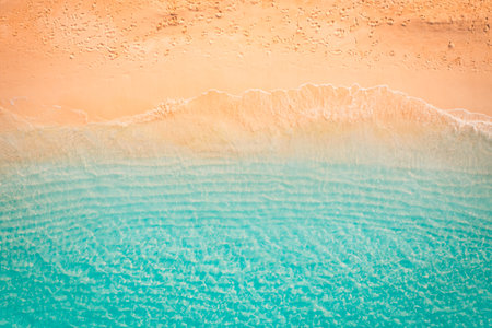 Tranquil aerial top view of golden sand beach with calm waves and peaceful shore, tropical...