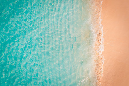 Tranquil aerial top view of golden sand beach with calm waves and peaceful shore, tropical Mediterranean landscape with relaxing summer vacation vibesの写真素材
