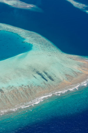 Aerial view of atoll reef lagoon and ocean in Maldives tropical paradise with turquoise waters...