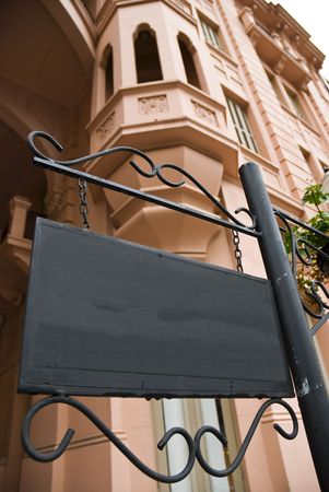 Dark wooden sign board with pink Victorian building in the background. Low angle shot.の写真素材