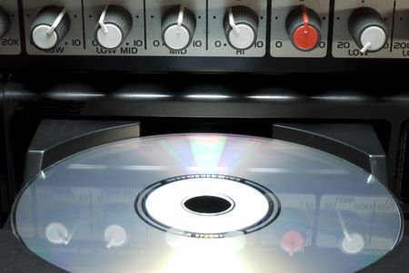 Detail shot of a CD in a player's drawer with crossover buttons on top. Front shot with dark...