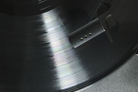 Cropped image shot directly from above of a record player needle, with LP underneath