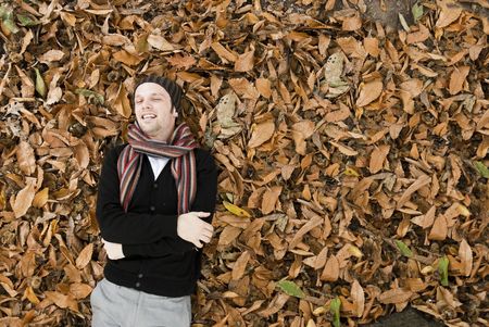High angle portrait of young man laying on the yellow leaves covered ground.の写真素材