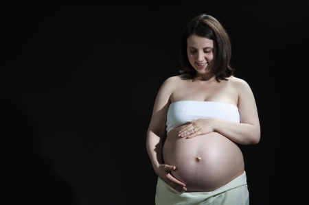 Portrait of happy young pregnant woman feeling her baby belly.の写真素材