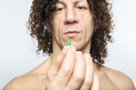Cropped shot of bare chested mediterranean man holding colourful pillの写真素材
